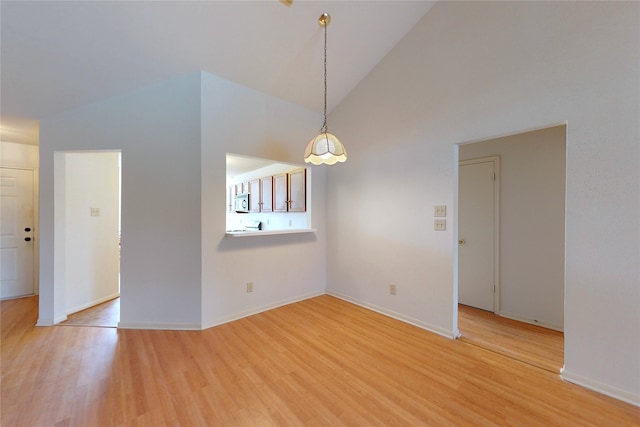 empty room with baseboards, light wood-style floors, and high vaulted ceiling