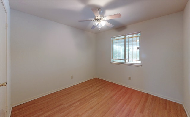 empty room featuring light wood finished floors, a ceiling fan, and baseboards