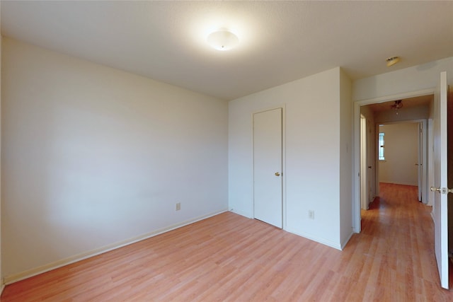 unfurnished bedroom with a closet, baseboards, and light wood finished floors