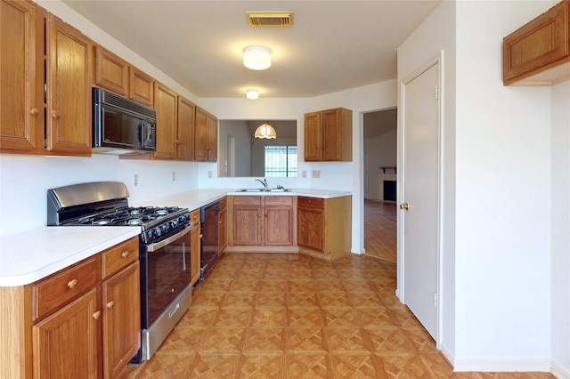 kitchen featuring visible vents, light countertops, brown cabinets, black appliances, and a sink