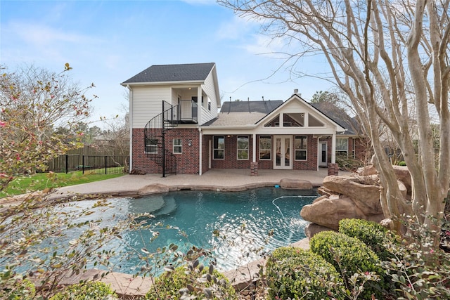 back of property featuring fence, french doors, a balcony, brick siding, and a patio area