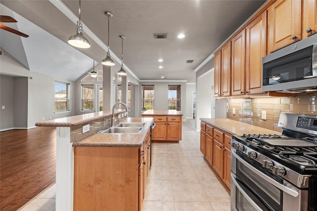 kitchen with visible vents, a center island with sink, ornamental molding, appliances with stainless steel finishes, and a sink