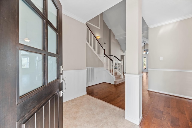 entryway with ornamental molding, stairs, and wood finished floors