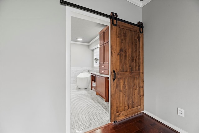 full bathroom with crown molding, a freestanding bath, vanity, wainscoting, and tile walls