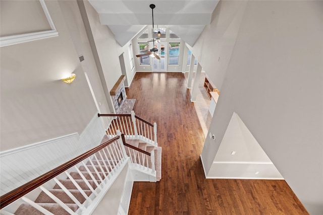 staircase featuring baseboards, high vaulted ceiling, wood finished floors, and a ceiling fan