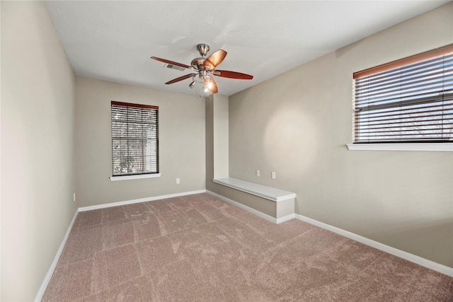 carpeted empty room with visible vents, a ceiling fan, and baseboards