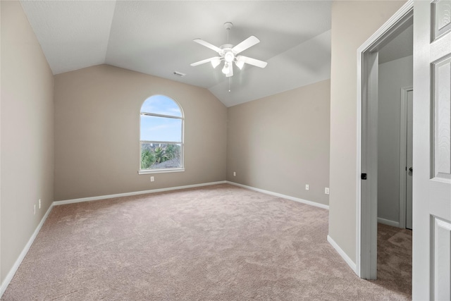 spare room with visible vents, baseboards, carpet floors, vaulted ceiling, and a ceiling fan