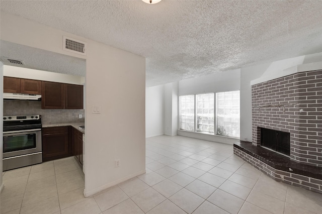 unfurnished living room featuring light tile patterned flooring, visible vents, a fireplace, and a textured ceiling