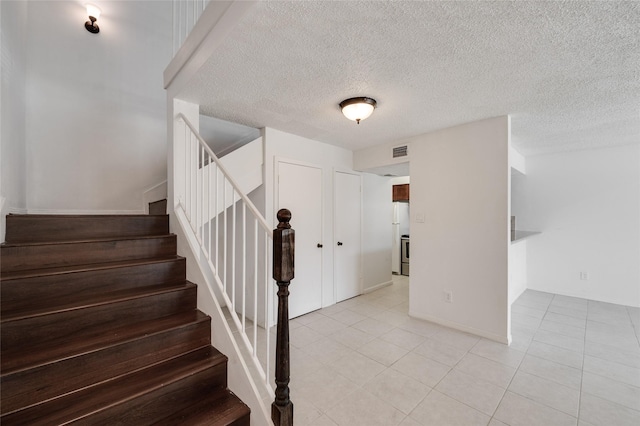 staircase featuring tile patterned flooring, visible vents, and a textured ceiling