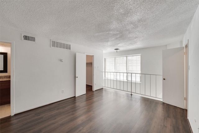 spare room featuring dark wood-style floors, visible vents, and a textured ceiling