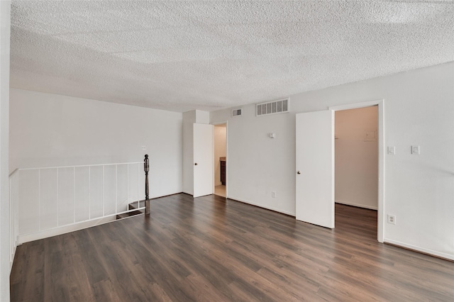 spare room featuring dark wood-style floors, visible vents, and a textured ceiling