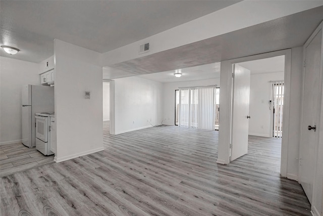 unfurnished living room with light wood-style flooring, baseboards, and visible vents