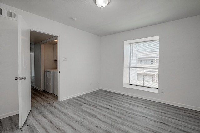 unfurnished room featuring baseboards, light wood-style floors, visible vents, and washer and clothes dryer