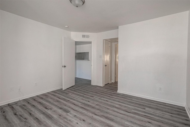 empty room with visible vents, baseboards, and wood finished floors