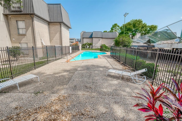 view of swimming pool with a patio area, a fenced in pool, and fence