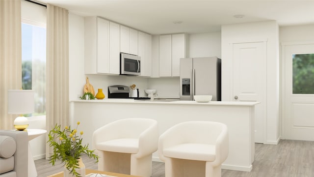 kitchen with light wood-style floors, appliances with stainless steel finishes, a peninsula, white cabinets, and light countertops