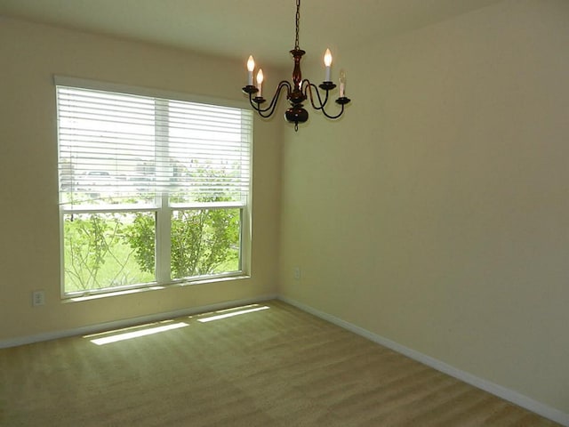 unfurnished room featuring a chandelier, baseboards, and wood finished floors