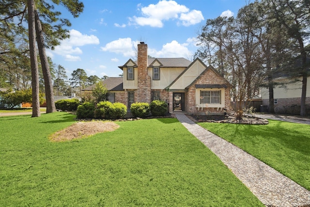 tudor house with brick siding, stucco siding, a chimney, and a front lawn