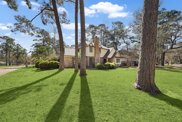 view of front facade featuring a front yard, brick siding, and a chimney