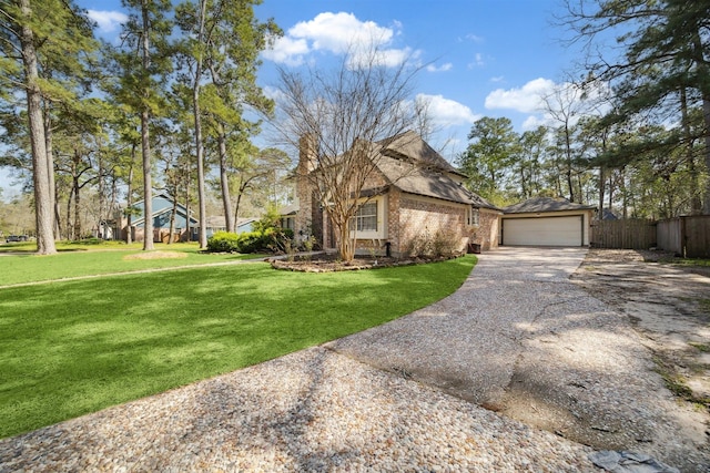 view of side of property featuring brick siding, fence, a lawn, a garage, and an outbuilding