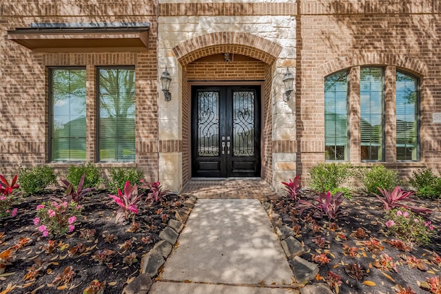 view of exterior entry featuring french doors and brick siding