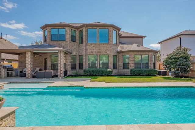 rear view of house featuring an outdoor pool, a patio, brick siding, and a ceiling fan