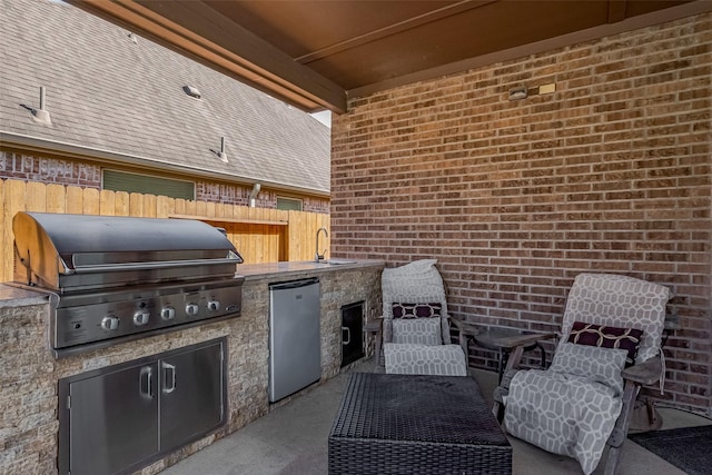 view of patio with an outdoor kitchen, a grill, fence, and a sink