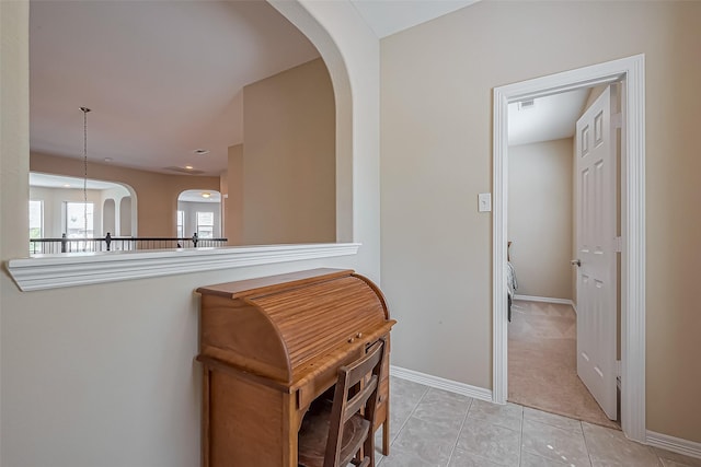 corridor with light tile patterned flooring, visible vents, arched walkways, and baseboards