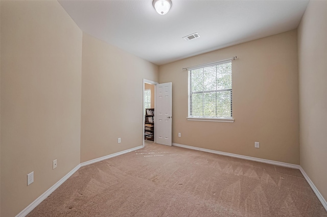 empty room with visible vents, light colored carpet, and baseboards