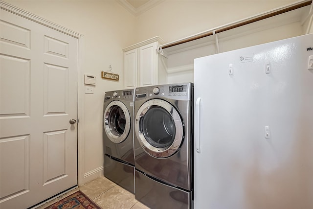 laundry area featuring ornamental molding, cabinet space, light tile patterned floors, and washer and clothes dryer