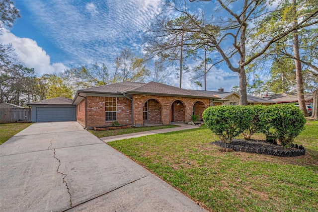 view of front of home with concrete driveway, fence, brick siding, and a front yard