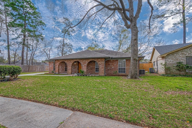 view of front of house with a front yard, fence, brick siding, and central AC