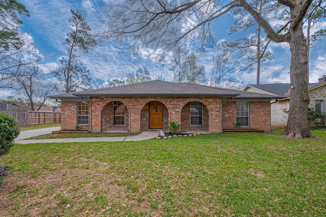 ranch-style home featuring brick siding, a front yard, and fence