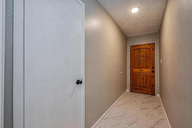 entryway with marble finish floor, a textured ceiling, and baseboards