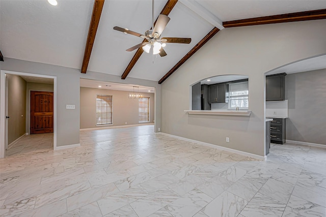 unfurnished living room with beam ceiling, ceiling fan with notable chandelier, and marble finish floor