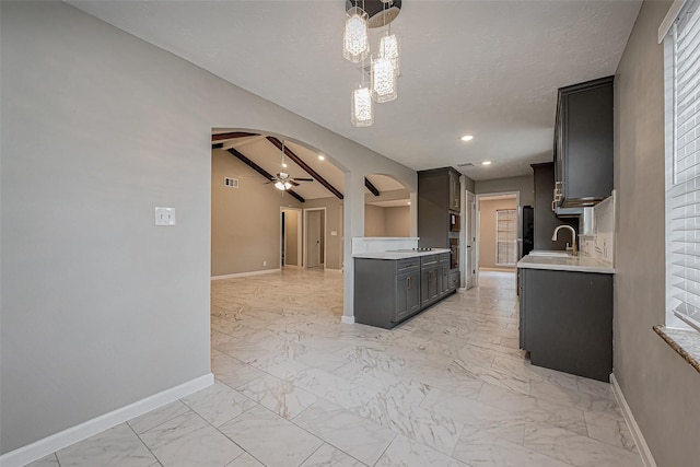 kitchen with arched walkways, a sink, light countertops, ceiling fan with notable chandelier, and marble finish floor