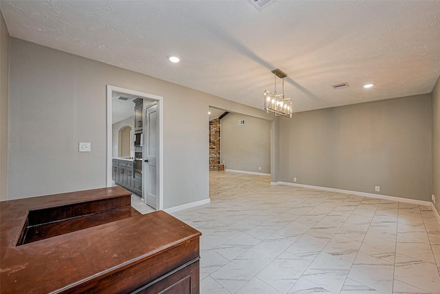 empty room with recessed lighting, marble finish floor, a textured ceiling, and baseboards