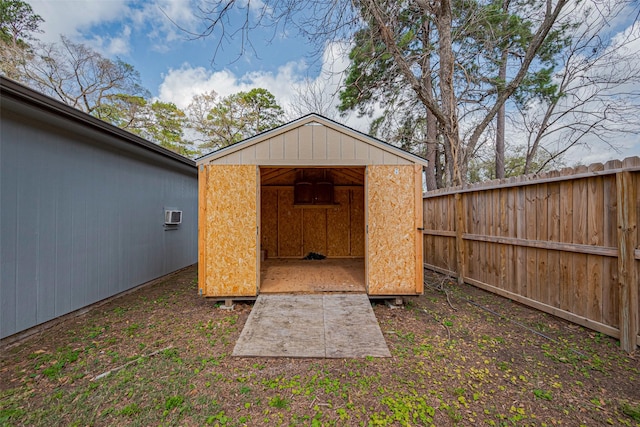 view of shed with a wall unit AC and a fenced backyard