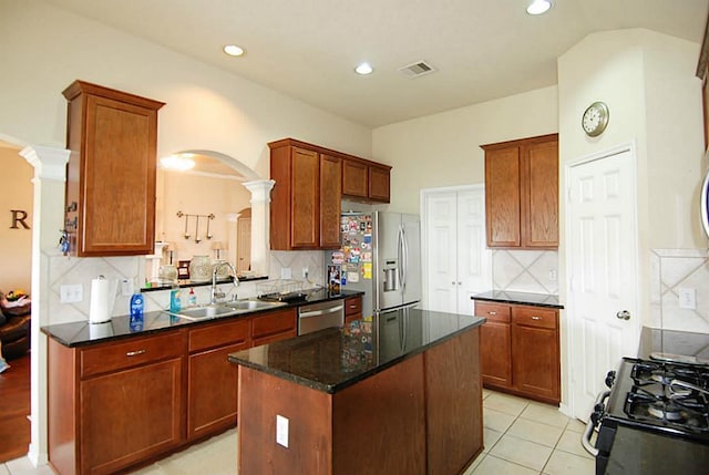 kitchen featuring visible vents, a sink, a kitchen island, stainless steel appliances, and arched walkways