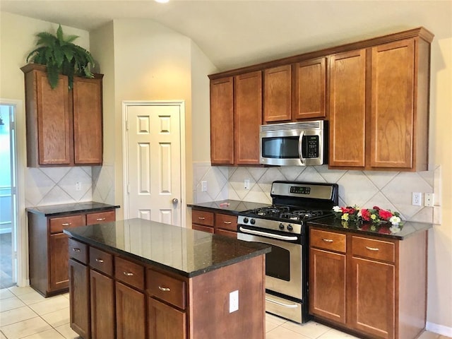 kitchen featuring light tile patterned floors, stainless steel appliances, decorative backsplash, and dark stone counters