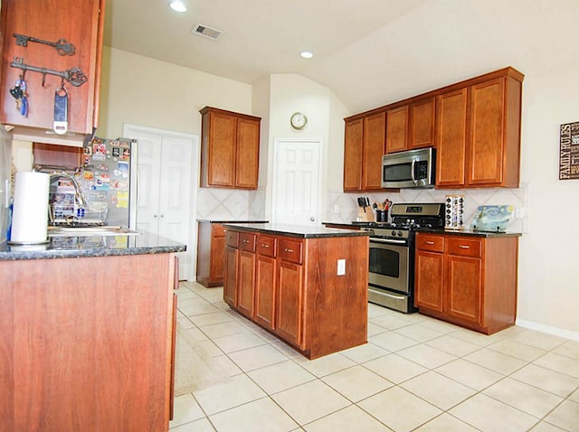 kitchen featuring light tile patterned floors, visible vents, lofted ceiling, stainless steel appliances, and tasteful backsplash