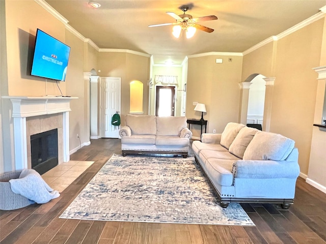 living room featuring arched walkways, wood finished floors, and a tiled fireplace