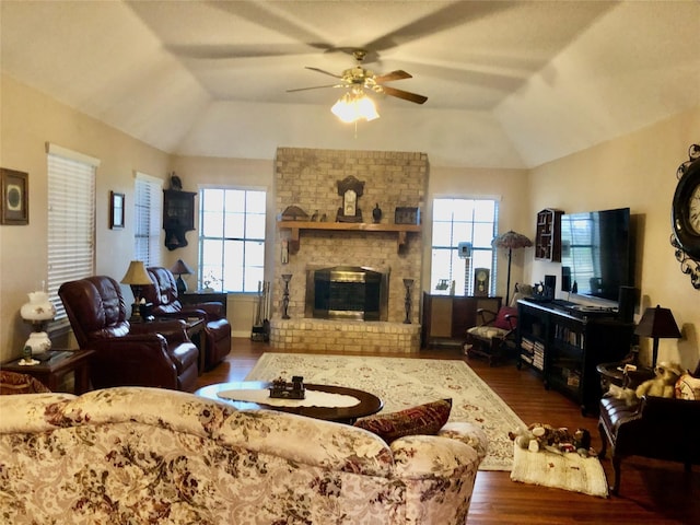 living area featuring a fireplace, lofted ceiling, wood finished floors, and a ceiling fan