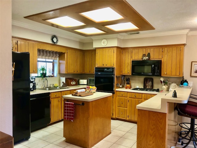 kitchen featuring black appliances, a peninsula, brown cabinetry, and light countertops