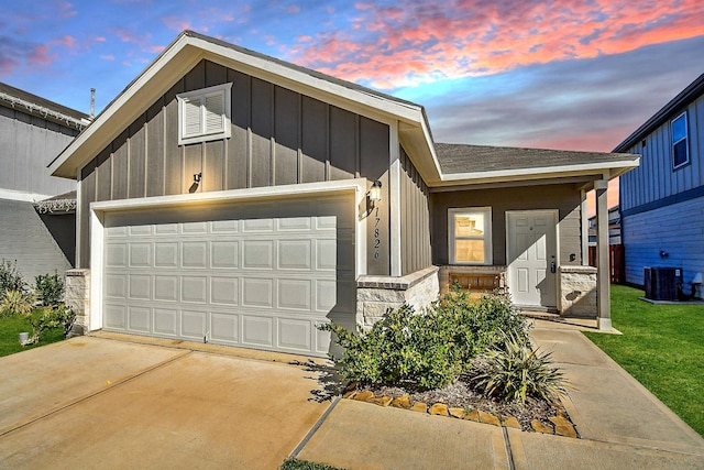 view of front of house featuring driveway, central AC, board and batten siding, a shingled roof, and a garage