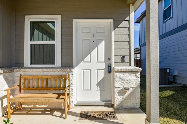 view of exterior entry featuring central air condition unit and stone siding