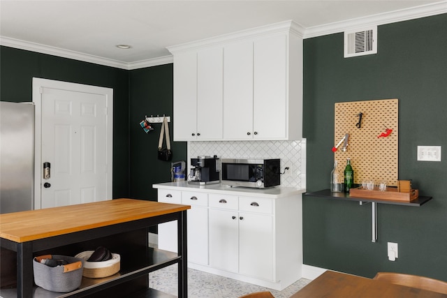 kitchen featuring visible vents, light countertops, ornamental molding, decorative backsplash, and stainless steel appliances