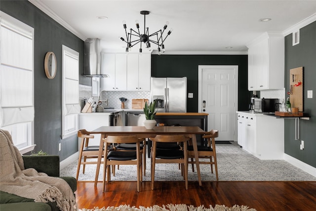 kitchen with a wealth of natural light, stainless steel appliances, crown molding, and wall chimney range hood