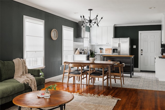 dining space featuring a chandelier, wood finished floors, a healthy amount of sunlight, and ornamental molding