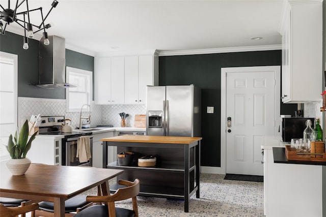 kitchen with a sink, butcher block countertops, stainless steel appliances, white cabinets, and wall chimney exhaust hood